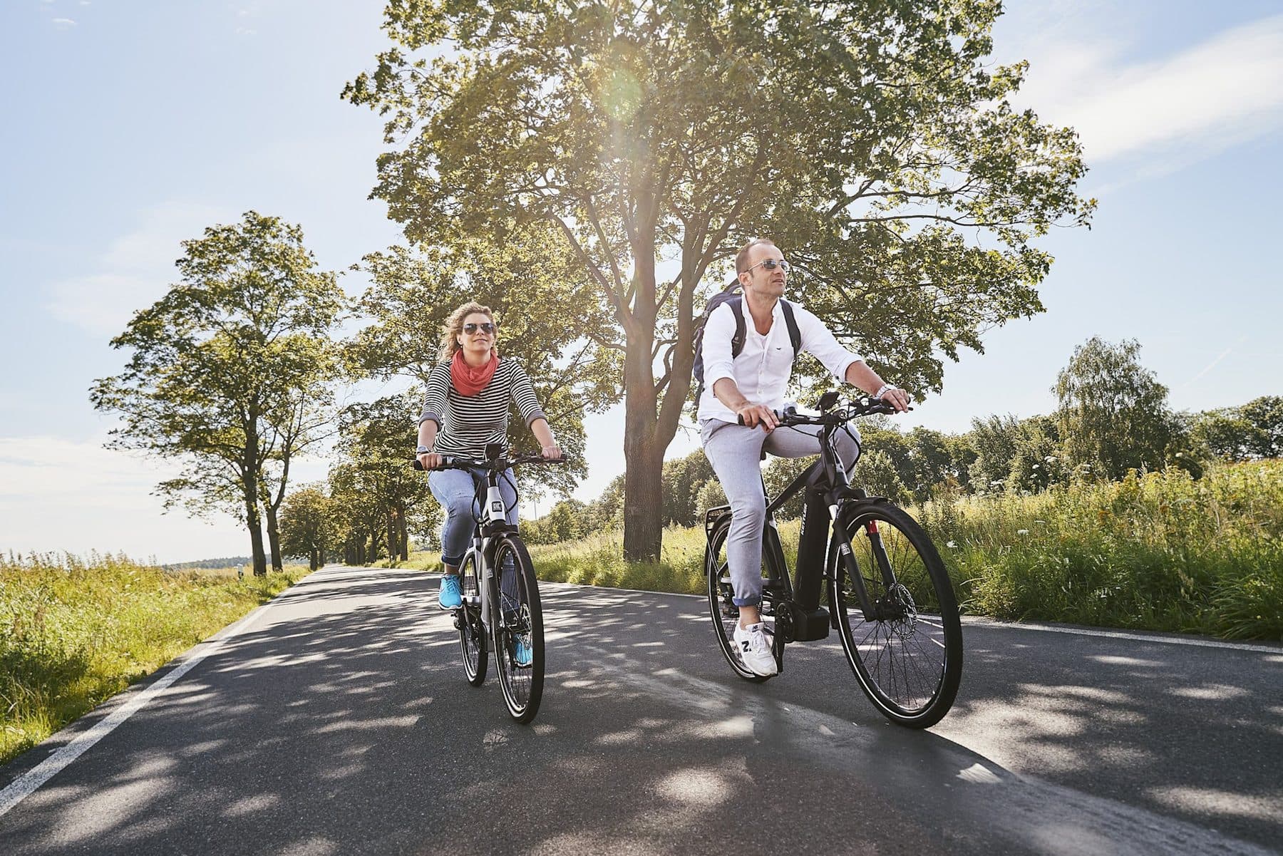 Paar auf Trekking e-Bikes auf einer Landstraße